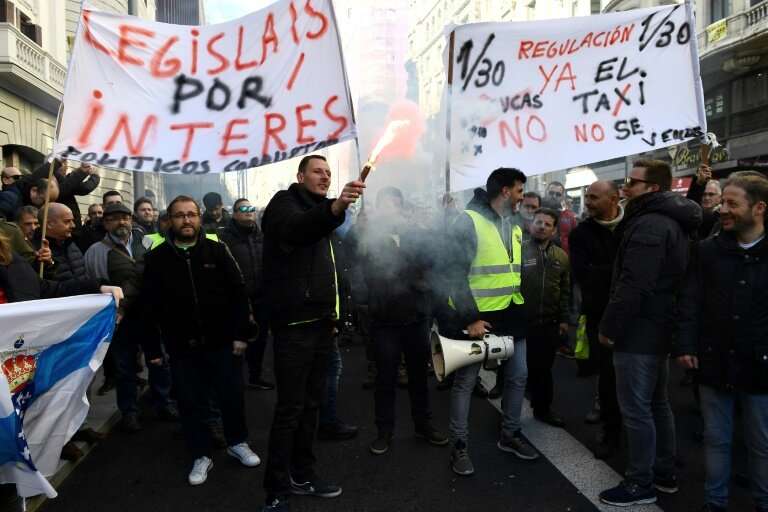 Taxi drivers hold flares and placards reading &quot;Regulation now&quot; during a demonstration in to protest against online rid