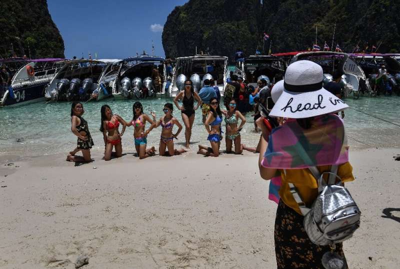 Tourists pose in Maya Bay before a row of boats in April 2018, shortly before the beach was ruled off-limits in a bid to protect