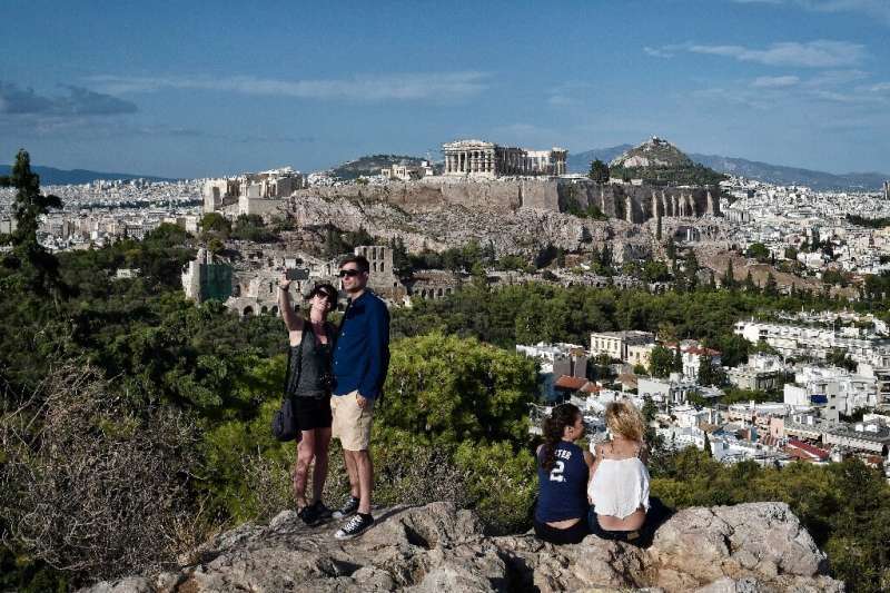 Tourists take a selfie with the Acropolis in the background