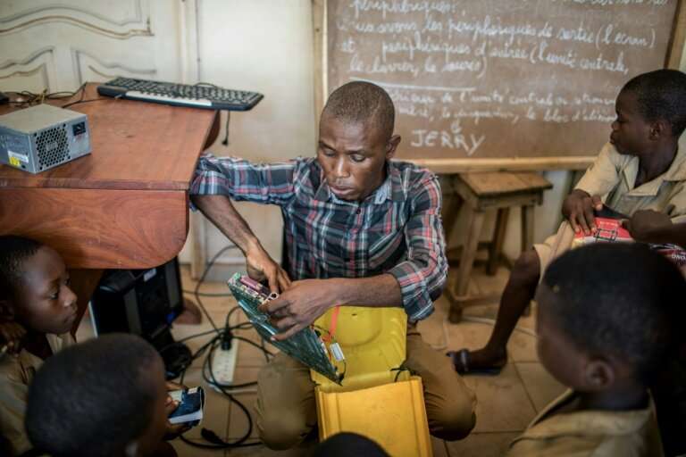 Trainer Raoul Letchede shows the kids the components they will use to assemble a makeshift computer in a 25-litre plastic contai