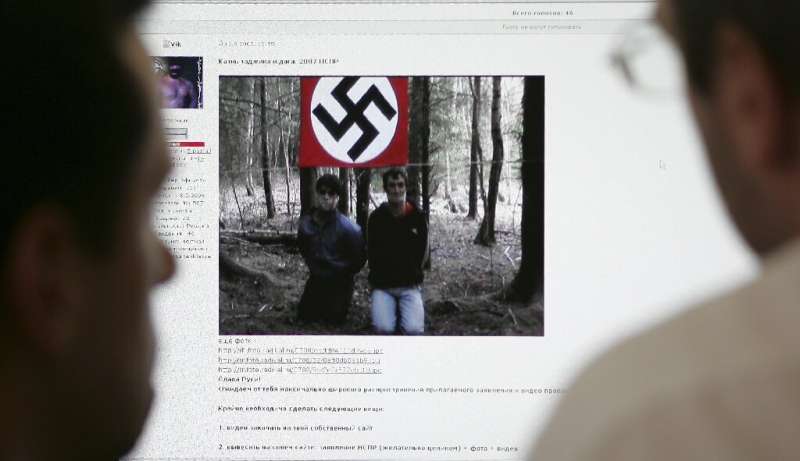 Two men look at the website of the United Slavic National-Socialists Forum on a computer in Moscow in 2007 which contained a vid