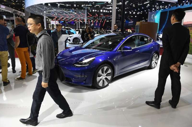 Visitors walk past a Tesla Model 3 at the Shanghai Auto Show in China on April 17, 2019