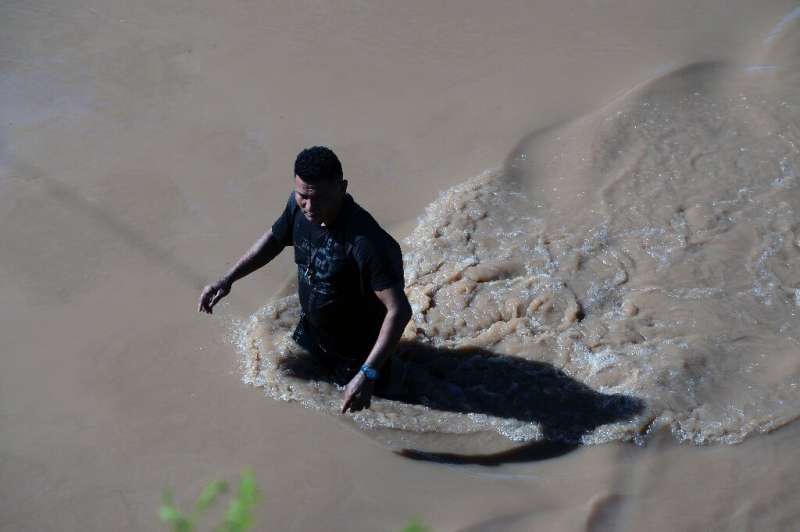 A man wades through water flooding the road from El Progreso to La Lima n Honduras
