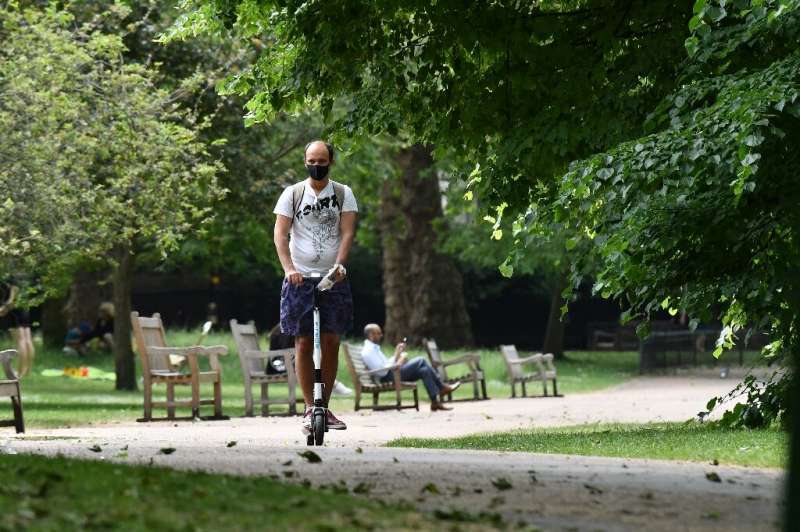 A man wears a facemask as he scooters through  St James's Park in central London on May 26 as lockdown measures are eased