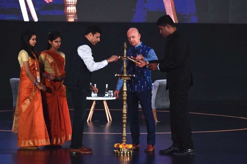 Amazon CEO Jeff Bezos (R) lights a traditional lamp along with Amit Agarwal (3L), senior vice president and country manager for 