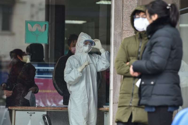 A nurse, wearing protective clothing, looks at a thermometer at a hospital in Wuhan—epicentre of the China virus outbreak
