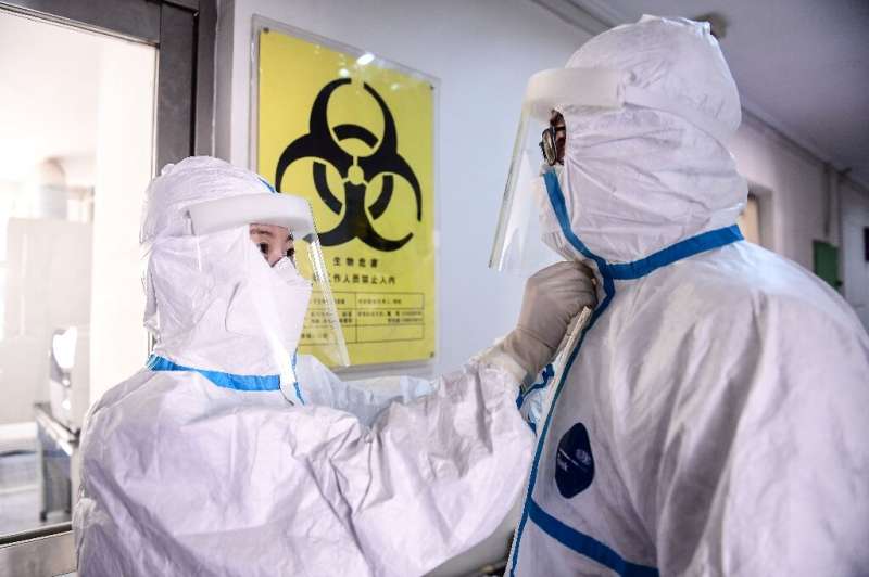A technician helps a colleague remove a protective suit after leaving a laboratory in Shenyang in China's northeastern Liaoning 