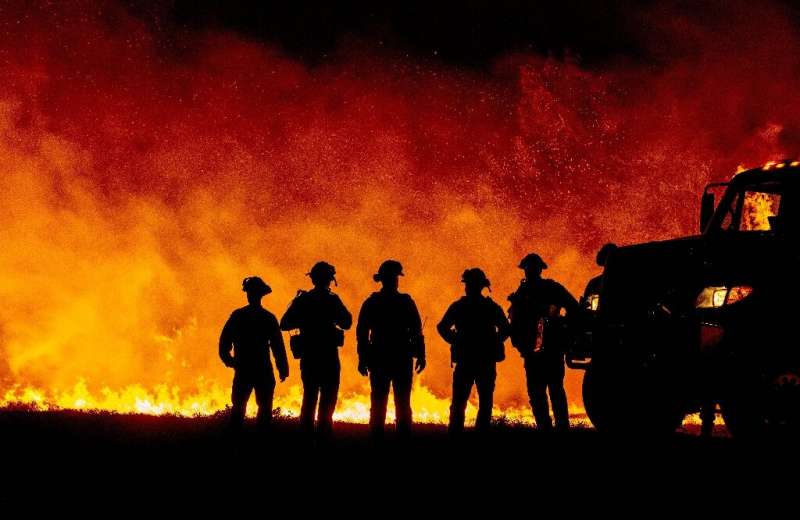 Butte County firefighters watch as flames quickly spread across a road at the Bear Fire in Oroville, California