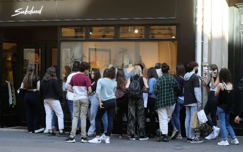 People queue in front of a shop in Paris on the first weekend after France eased lockdown measures taken to curb the spread of t