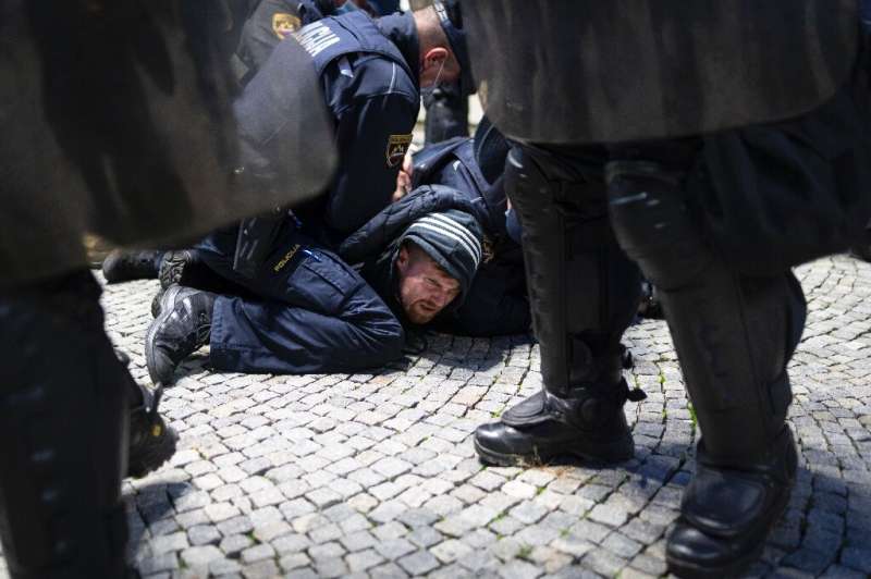 Police officers hold down a protester during a rally against coronavirus restrictions in Ljubljana, Slovenia