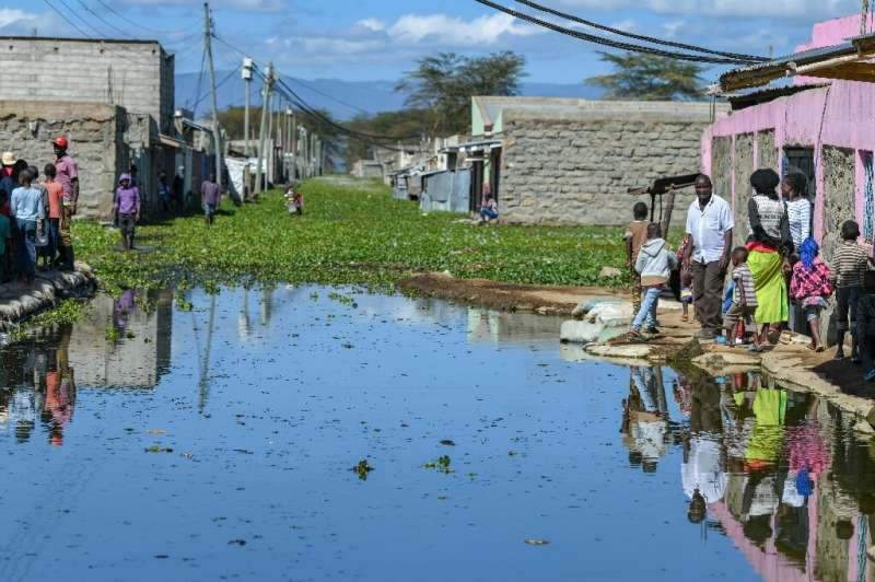 Residents of Kihoto estate on the shores of Lake Naivasha stand on elevated pavements outside their homes after the lake inundat