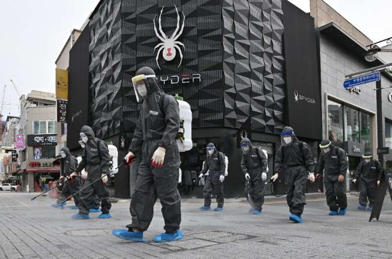 South Korean health officials from Bupyeong-gu Office wear protective gear to spray disinfectant at a shopping district in Inche