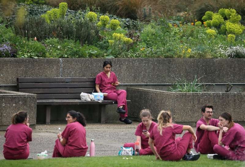 Medical staff from Britain's National Health Service (NHS) take a break outside St Thomas' Hospital in central London