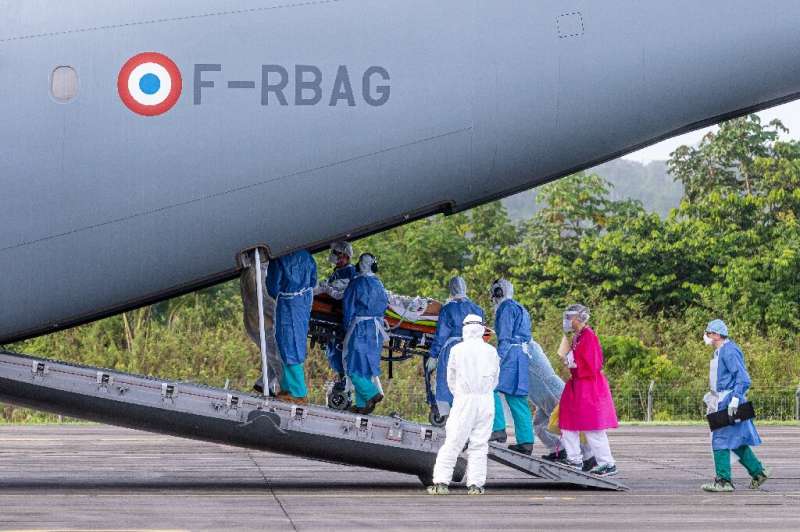 Medical staff carry a patient infected with Covid-19 into an Airbus A400M at an air-base in Matoury, Guiana