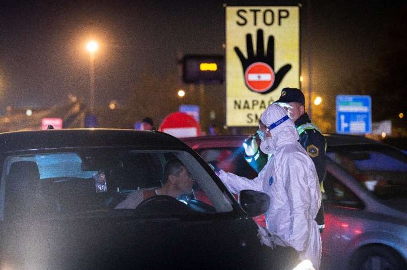 A medical worker measures body temperatures of motorists passing the Slovenian-Italian border crossing near Nova Gorica