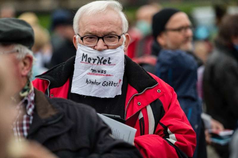 German Chancellor Angela Merkel urged public support for new shutdowns but this protester in Dresden was unimpressed—he says she