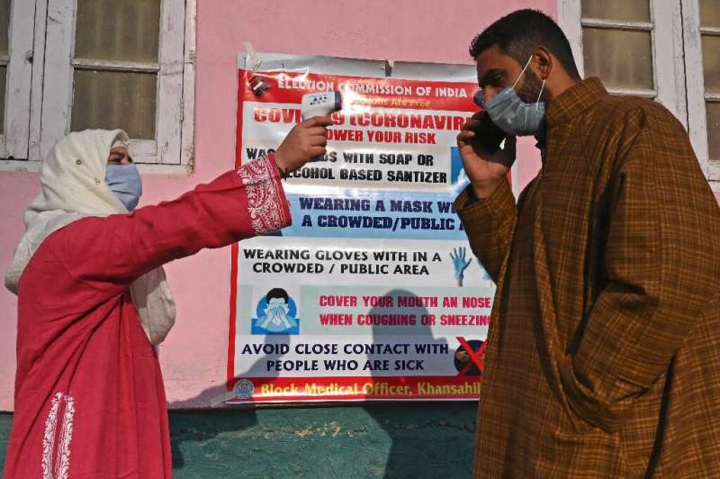 A health worker checks the temperature of a voter in India's Kashmir state