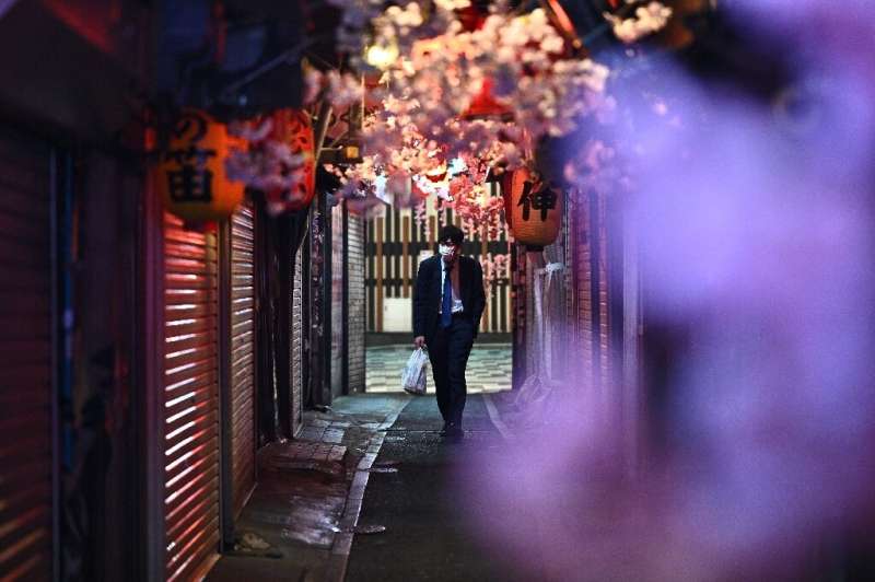 A man wearing a face mask walks along Omoide Yokocho in Tokyo