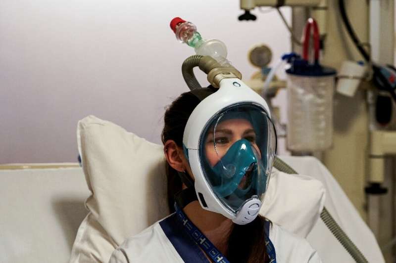 A medical worker tests a Decathlon snorkeling mask, with a 3D-printed respiratory valve fitting attached, at the Erasme Hospital