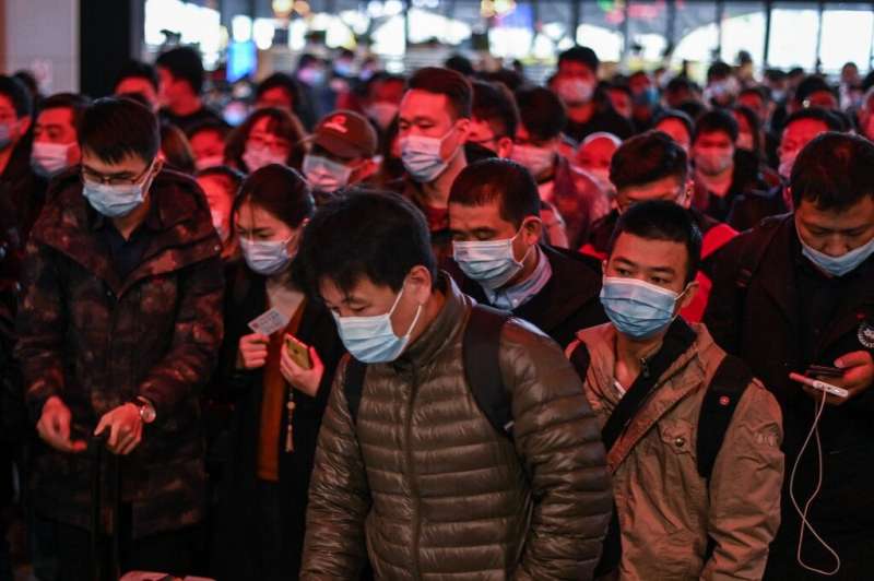 Passengers wearing face masks walk to their train at the main railway station in Wuhan, China
