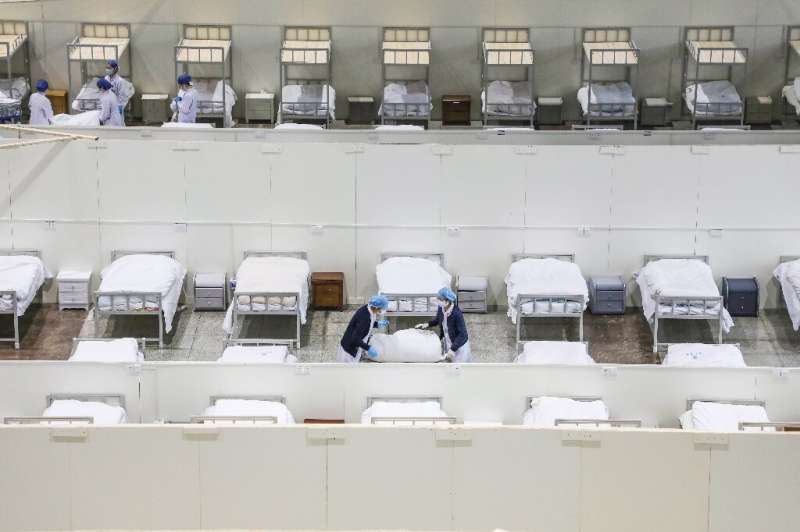 Medical staff set up beds for patients displaying mild symptoms of the coronavirus at an exhibition centre converted into a hosp
