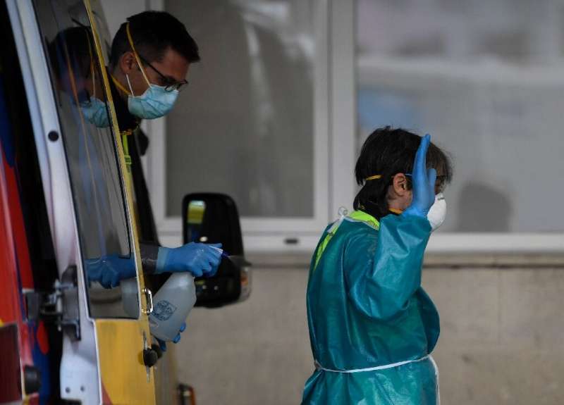 Healthcare workers disinfect their protective gear at a hospital in Madrid in Spain, one of the worst-hit countries