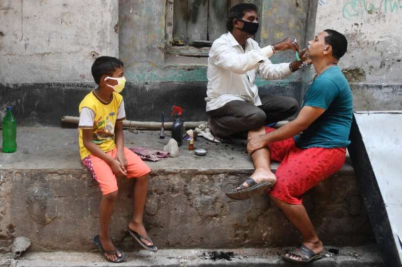 A barber wearing a facemask attends to a customer in Kolkata during a government-imposed nationwide lockdown