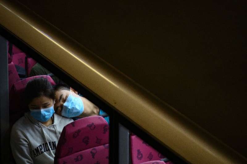 A couple wearing face masks sit in the upper deck of a double-decker bus in Hong Kong