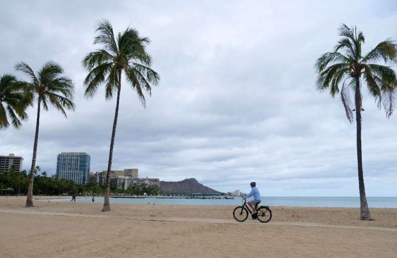 A cyclist rides along an empty Waikiki Beach in Honolulu, Hawaii as Hurricane Douglas veers northward, sparing Oahu from a direc