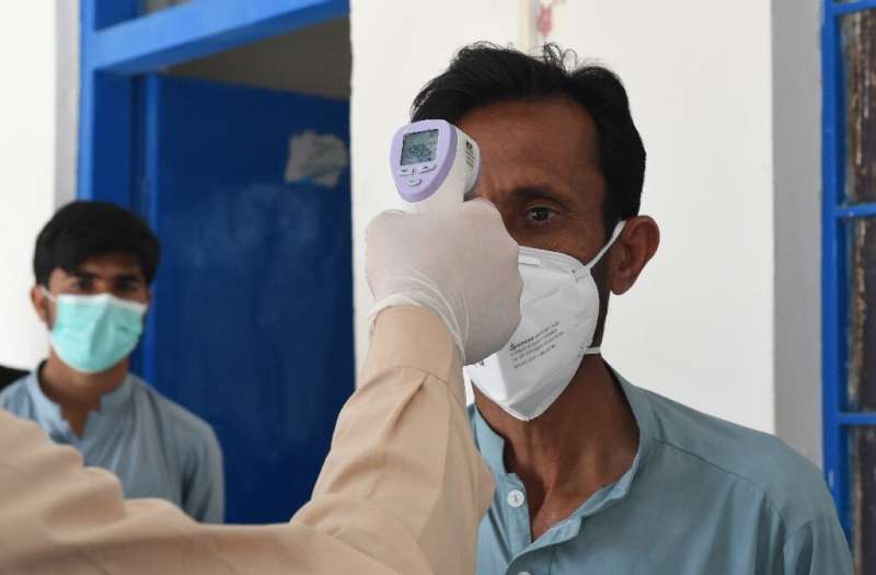A doctor checks the body temperature of a man returning from Iran at a quarantine zone to test for the COVID-19 coronavirus in t