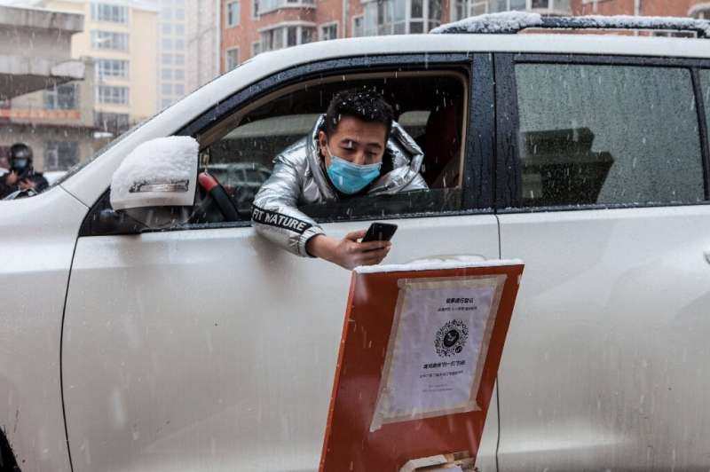 A driver scans a QR code to register information before entering a community in the border city of Suifenhe, in China's northeas