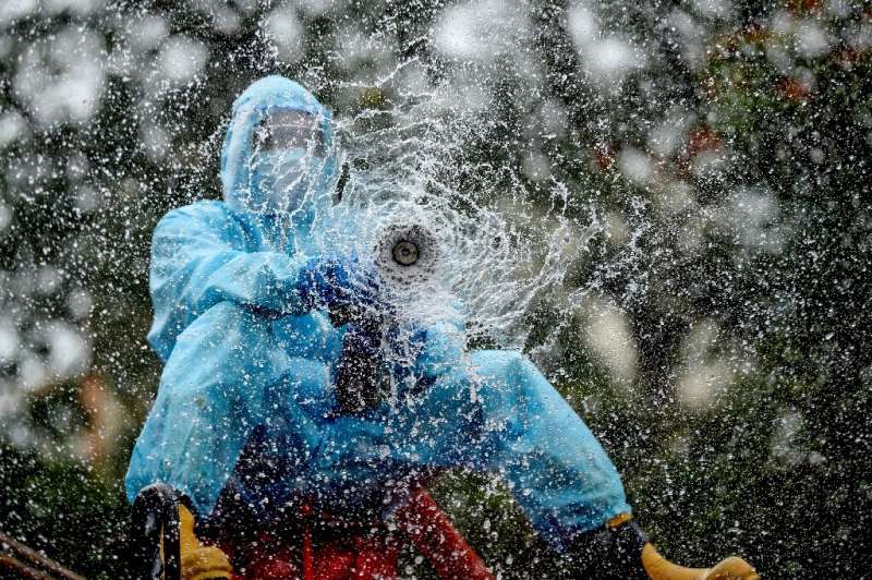 A firefighter sprays disinfectant as a preventive measure against the spread of the COVID-19 coronavirus in a containment zone i