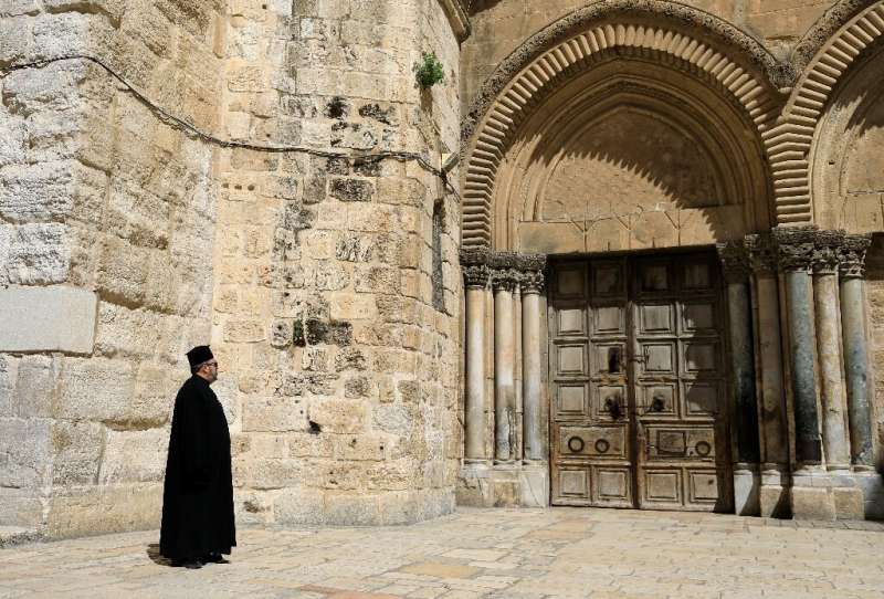 A Greek Orthodox priest gazes at the closed door of the Church of the Holy Sepulchre in the Old City of Jerusalem following the 