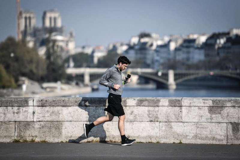 A jogger runs across a bridge in central Paris - joggers will have to keep 10 metres apart once the lockdown ends on May 11
