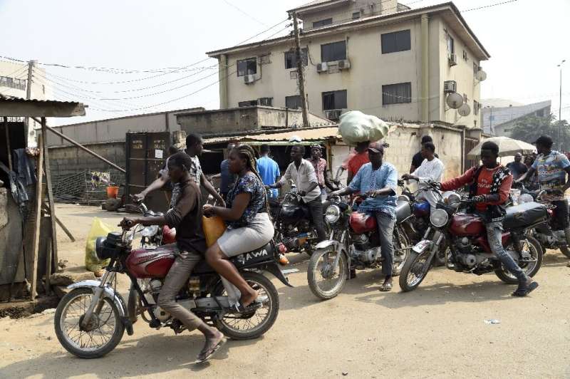 A lady rides on the back of a motorbike taxi in Lagos despite a ban on their use