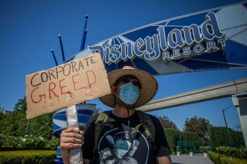 A man holds a sign in front of Disneyland Resort calling for higher safety standards before its reopening  amid the coronavirus 