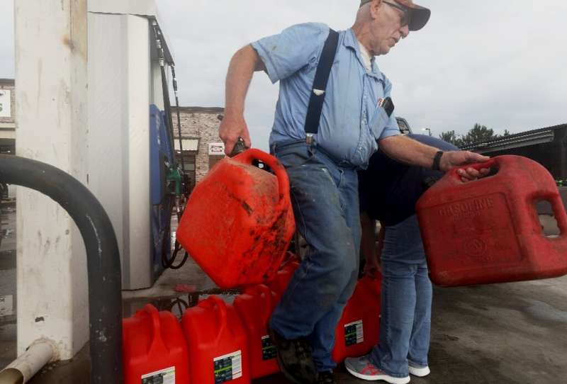 A man returns unfilled cans back to a truck after finding there was no gasoline left at a station in Lacassine, Louisiana as peo