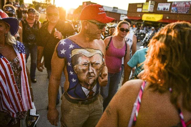 A man walks down Main Street in Sturgis, South Dakota, showing off his chest painted with a portrait of President Donald Trump d