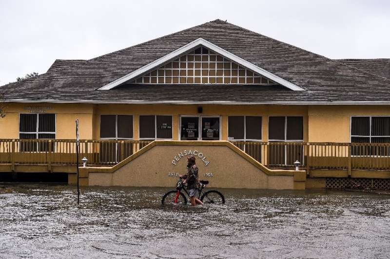A man walks with his bicycle through a street flooded by rains from Hurricane Sally in downtown Pensacola, Florida
