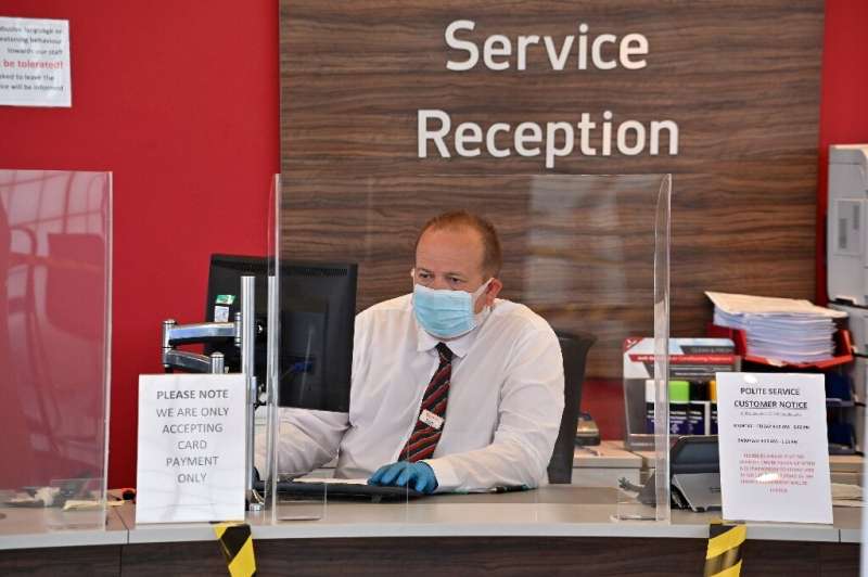 An employee dons a face mask and gloves and sits behind a perspex screen to receive customers—many industry experts expect it wi