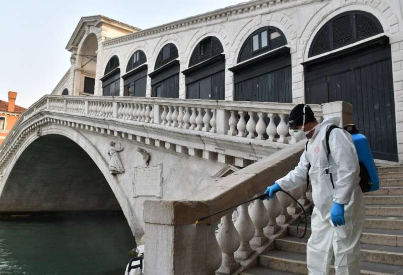 An employee of the municipal company Veritas sprays disinfectant in public areas at the Rialto Bridge in Venice