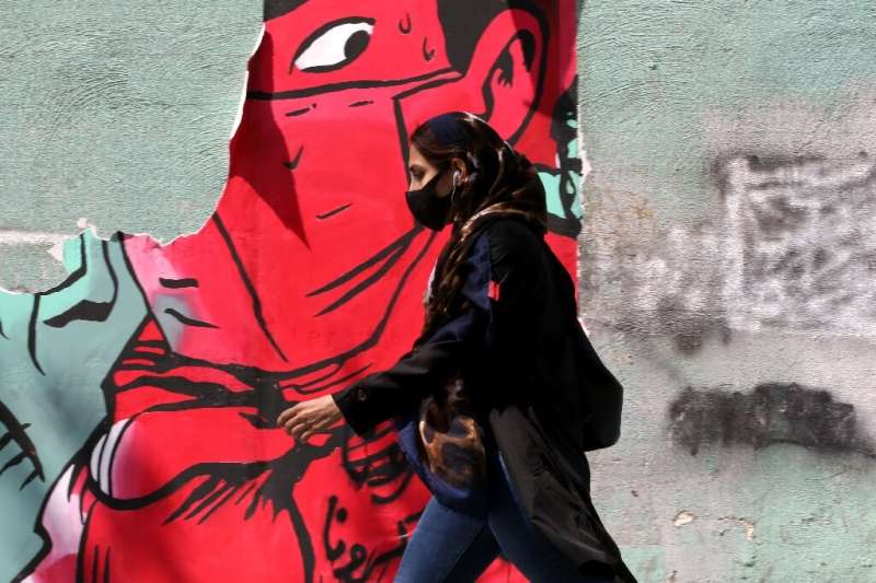 An Iranian woman walks past graffiti in Tehran