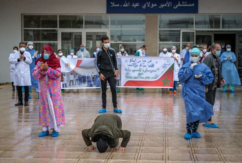 A patient who recovered from Covid-19 kisses the ground and another rejoices with medical staff as they leave a hospital in the 