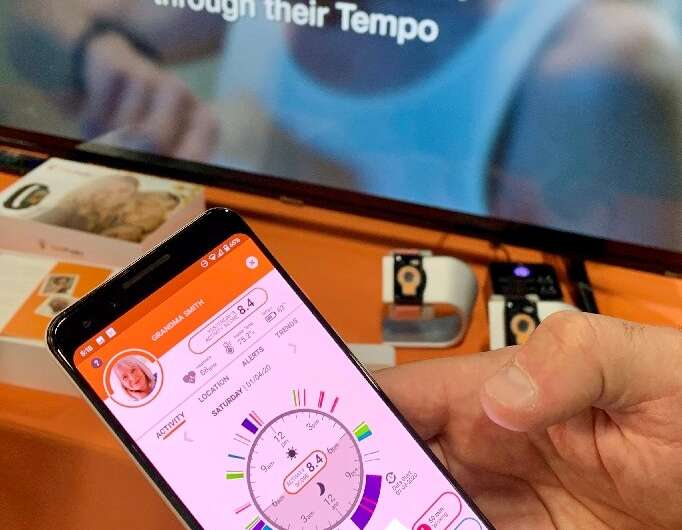 A person holds up the CarePredict app, which monitors seniors' daily activity and behavior patterns and alerts caregivers in cas