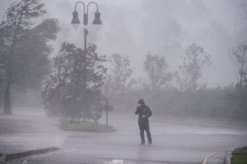 A reporter covers his face as Hurricane Delta makes landfall in Lake Charles, Louisiana on October 9, 2020