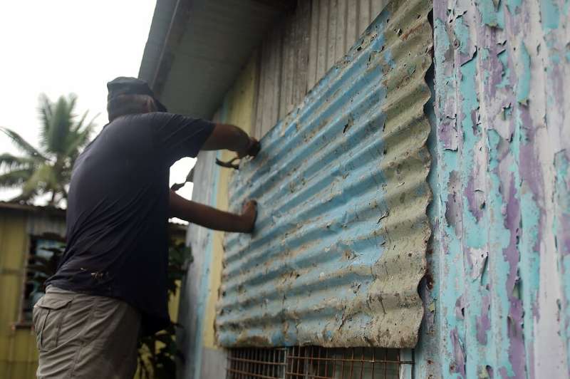 A resident secures his house by placing steel sheets on the windows in Fiji's capital Suva on December 16, 2020, ahead of super 