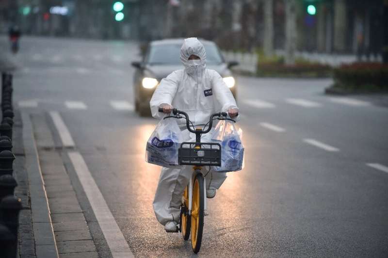 在中国中部湖北省武汉，一名穿着防护服的居民骑着自行车