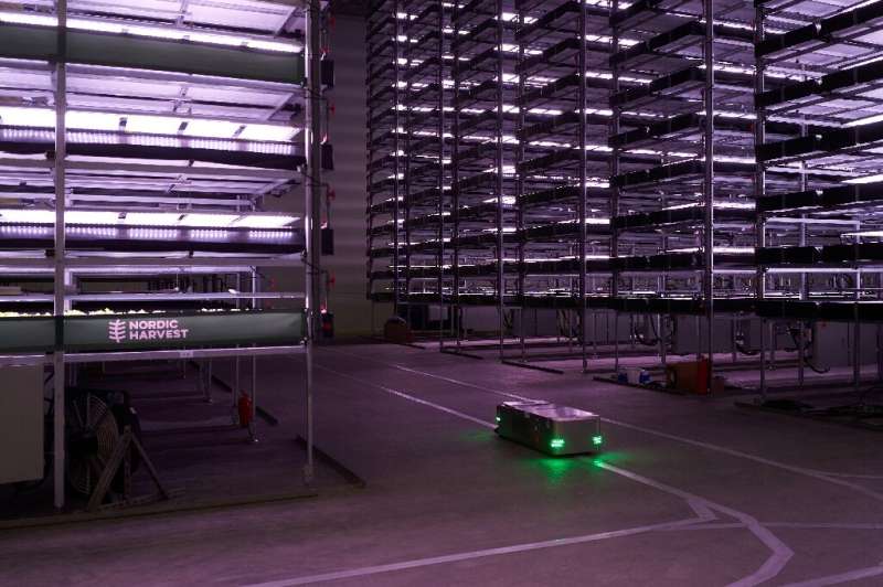 A robot, used to plant seeds and check the plants while growing, moves past vertical racks at  'Nordic Harvest' in Taastrup, a s