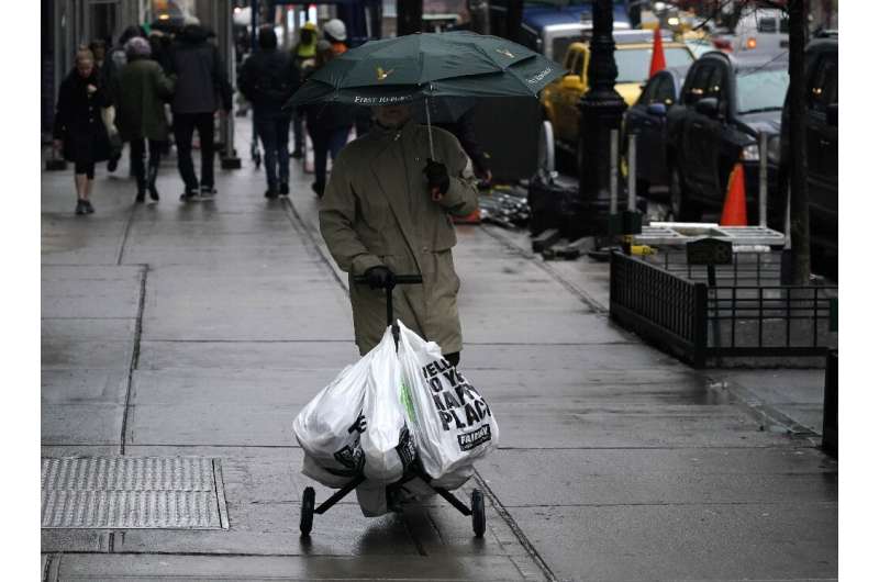 A shopper with groceries in plastic bags walks in New York's Upper East Side neighborhood on February 28, 2020, ahead of the sta