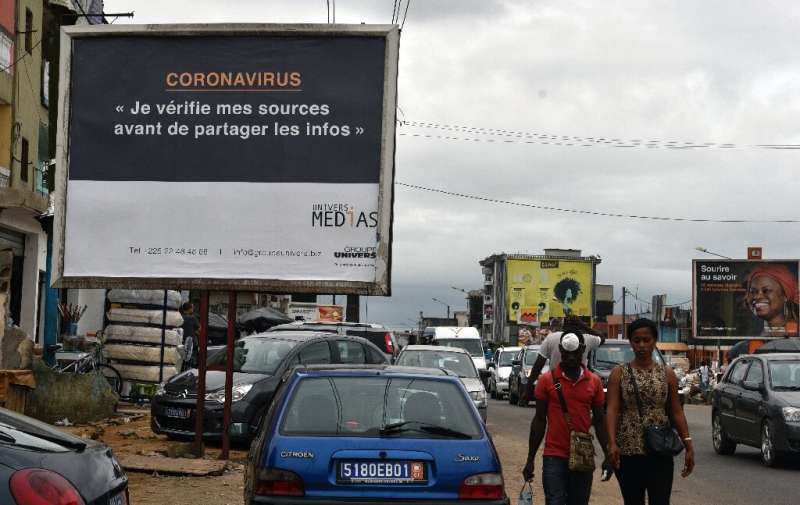 A sign in Abidjan reads 'Coronavirus - I check my sources before sharing news' to warn people against fake news and misinformati